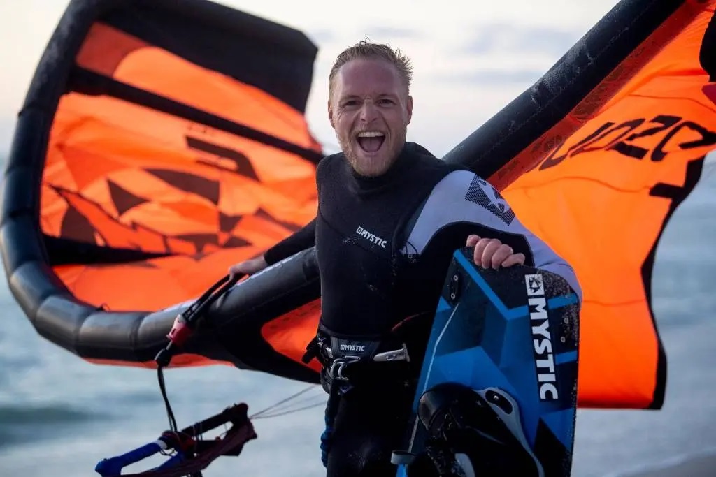 lächelnder Kitesurfer mit Ausrüstung nach einer Big-Air-Kitesurf-Session