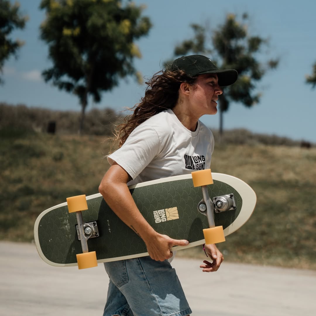 Donna con surfskate Long Island verde in mano