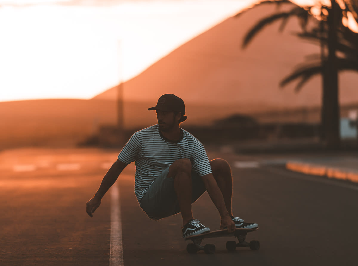 Hombre girando con surfskate en carretera al atardecer