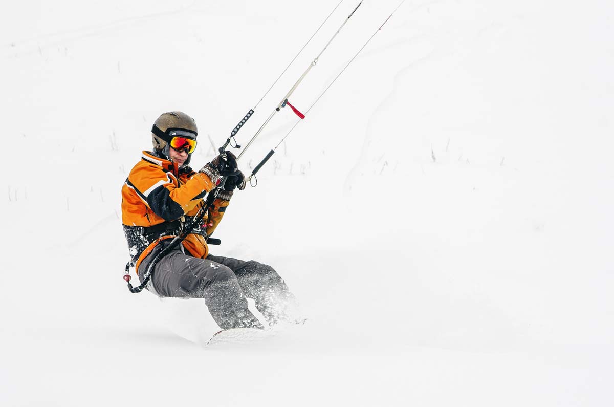 rider snowkite glissant sur la neige avec barre de contrôle