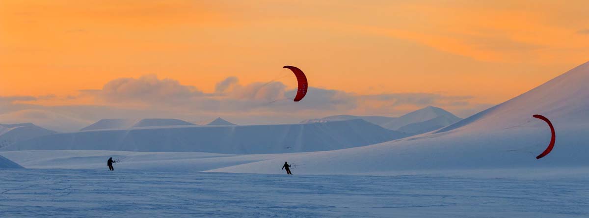 snowkite al tramonto con vele su distese di neve
